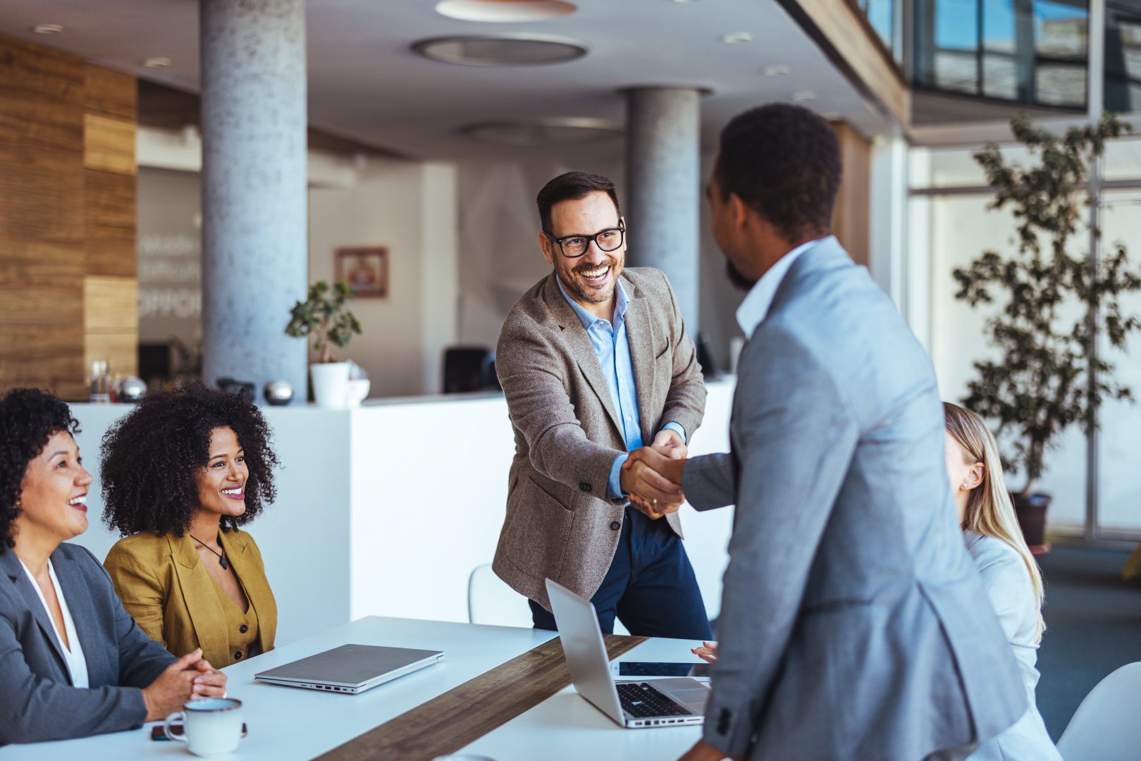 Business Team Meeting With Handshake and Smiling Team Members in Office Environment